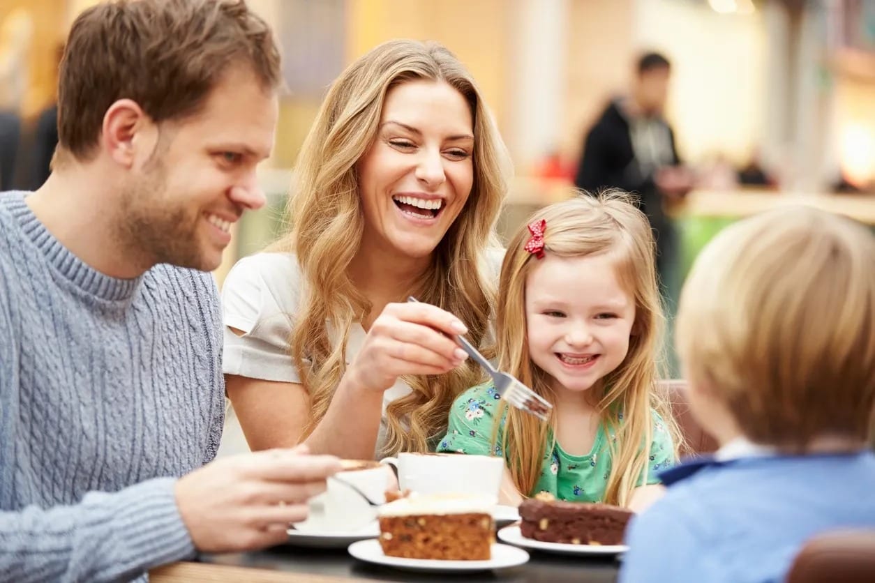 A family sitting at the table eating cake.